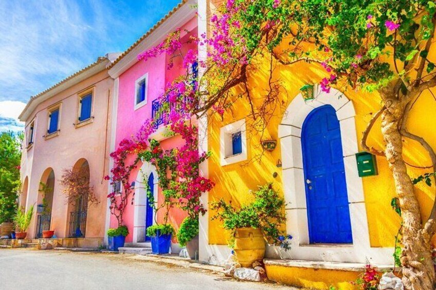 A colorful building with pink and yellow walls, blue doors, and pink flowers. 2