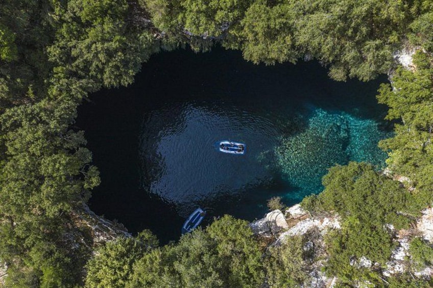 A lake surrounded by dense forest, with two boats anchored in the water. 2