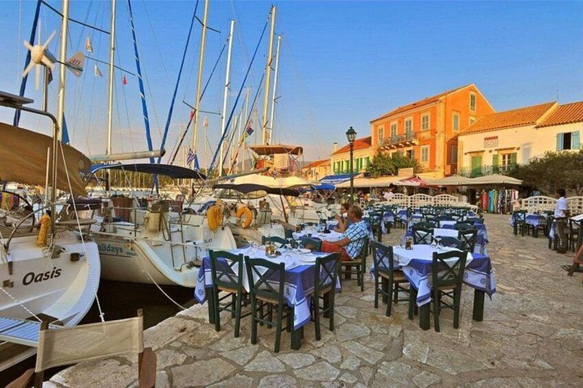 A marina with boats docked, outdoor tables and chairs, and a building in the background. 3