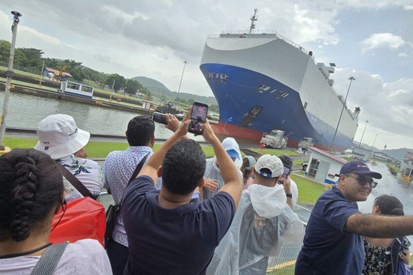 A large ship docked at a port with people taking photos. 2