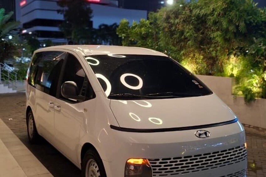 A white minivan parked on a sidewalk at night. 5