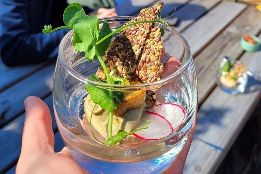 A clear glass bowl with a salad, including greens, radish slices, and seeds, held by a person. 5