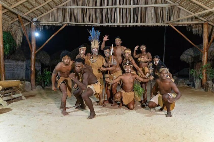 Un gruppo di persone in abiti tradizionali che posano sotto una struttura con tetto di paglia. 5