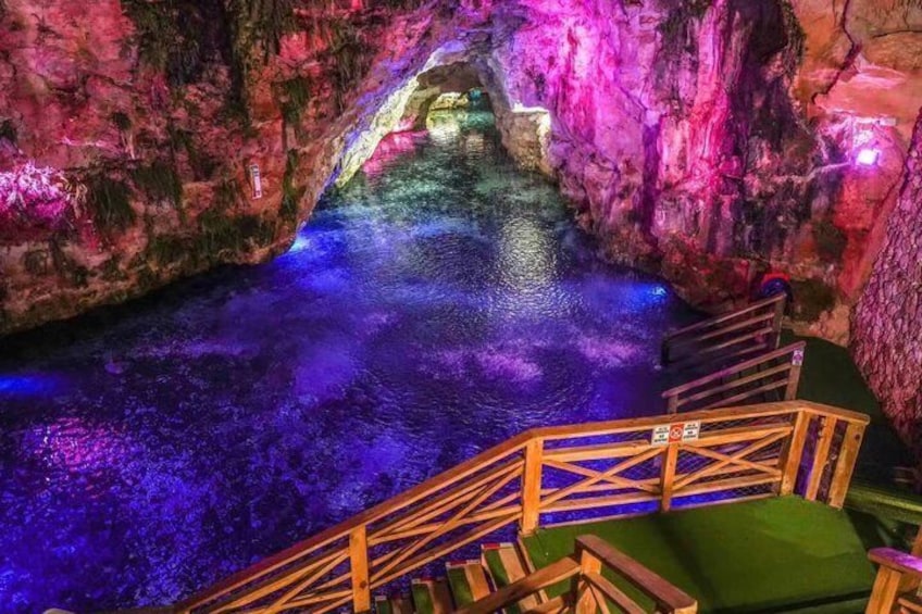 Una grotta con un ruscello, scale di legno e illuminazione colorata. 3