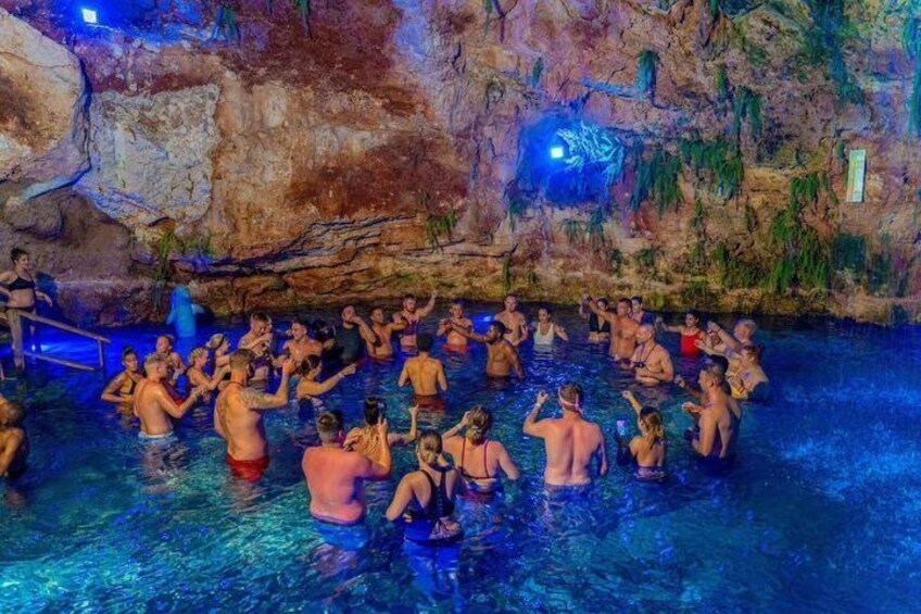 Un gruppo di persone in una piscina naturale con pareti rocciose e un soffitto simile a una grotta. 2