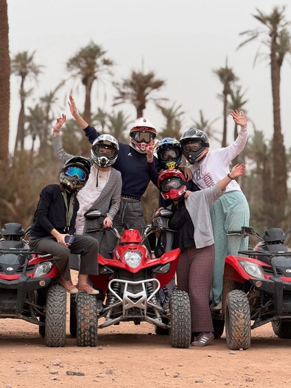 A group of people posing with ATVs in a desert landscape with palm trees. 4