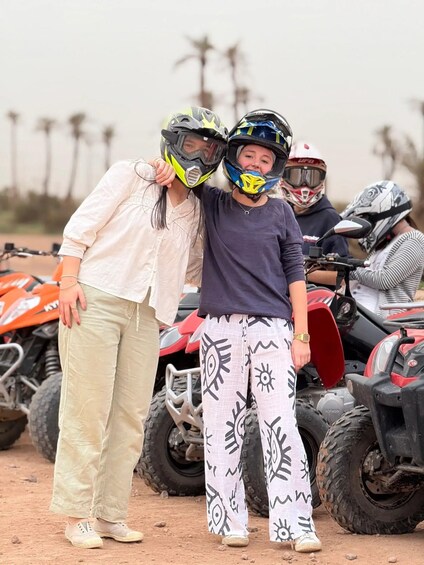 Two people wearing helmets, standing in front of ATVs. 3