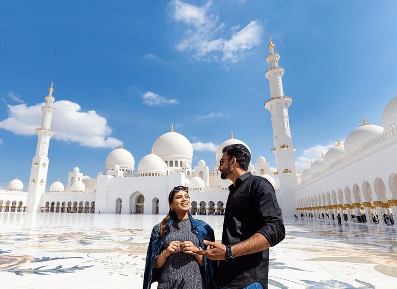 Ein großes, weißes Gebäude mit Kuppeln und Minaretten, bewölkter, blauer Himmel und einem gemusterten Boden. 1