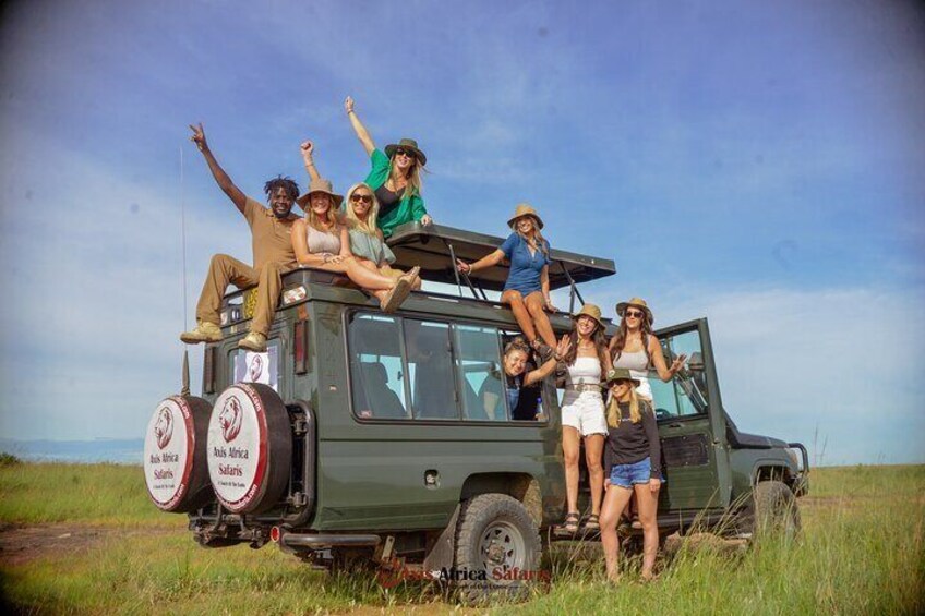 A group of people on a safari vehicle in a grassy field. 1