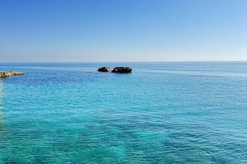 A clear blue sea with visible rocks and a clear sky. 2