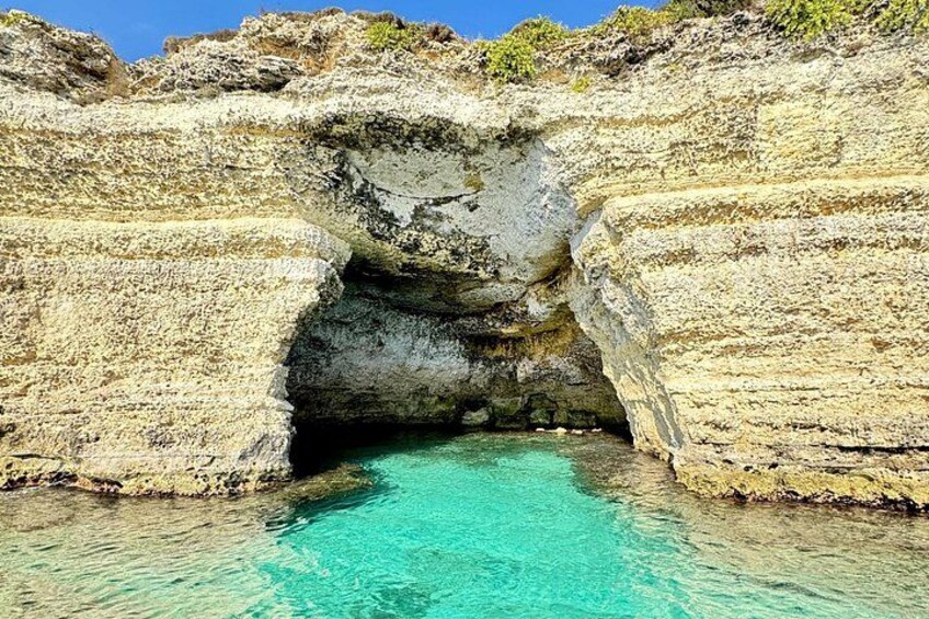 A natural rock formation with a clear blue pool at its base. 5