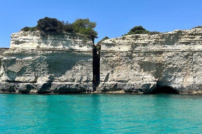 A coastal cliff with a narrow passage leading into a cave. 1
