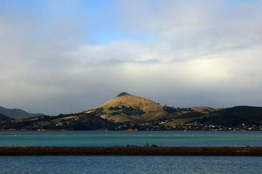 A coastal landscape with a hill, a body of water, and a small settlement. 3