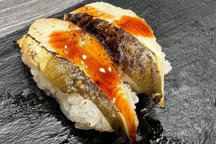 En sushi rulle med fisk, ris og sauce på en mørk skiferplade. 1
