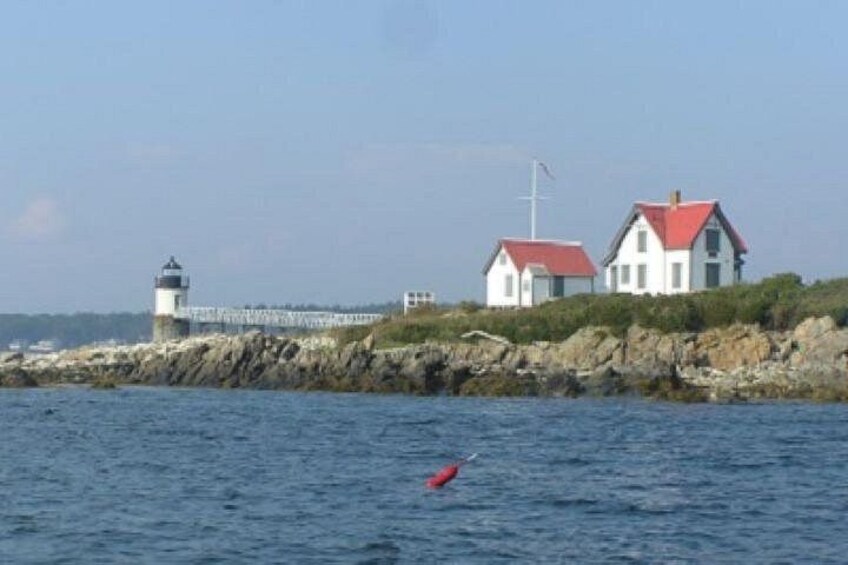 A lighthouse, a white house with a red roof, and a rocky shoreline. 2