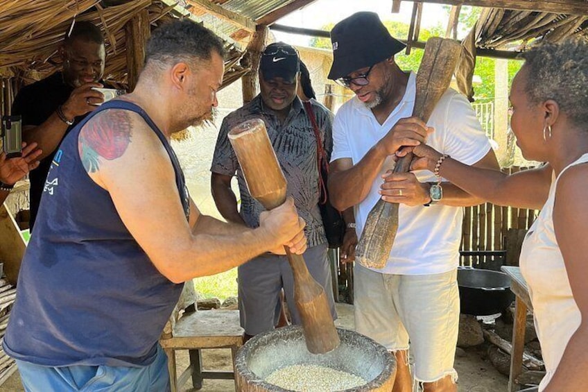 People using a large wooden tool to process grains. 3