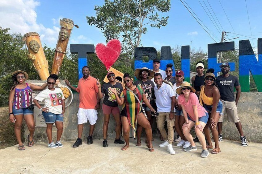 A group of people posing in front of a sign with the word 'PALENQUE' and a heart-shaped decoration. 4