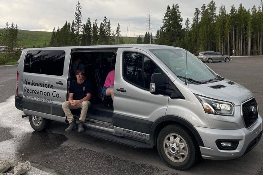 A silver van with 'Yellowstone Recreation Co.' on the side parked on a wet road. 2