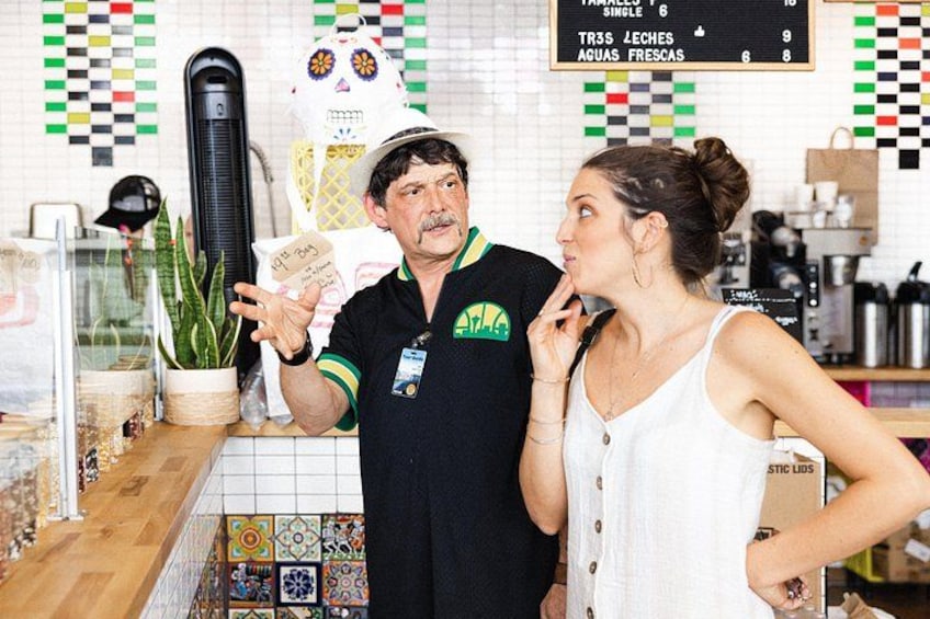 A person holding a card in a cafe with a menu board in the background. 3
