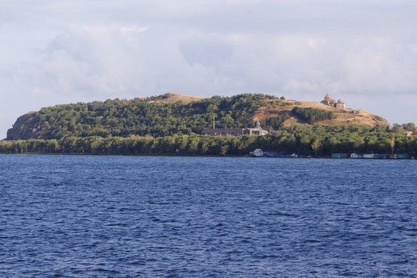 Un paisaje costero con una colina cubierta de vegetación y un pequeño edificio en la cima. 3
