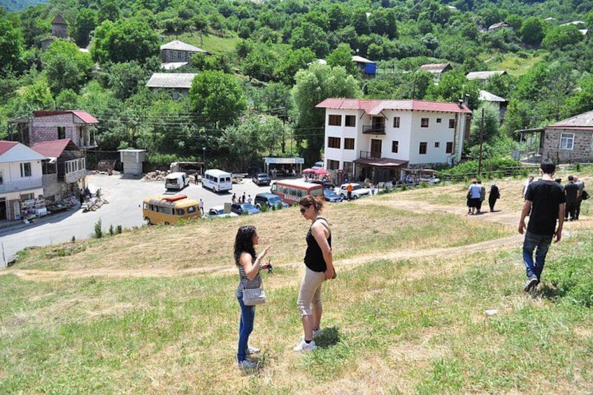 Un paisaje montañoso con un pequeño pueblo, edificios y algunas personas caminando. 4