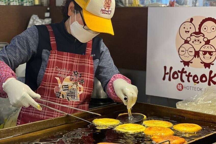 A person cooking at a hotdog stand. 3
