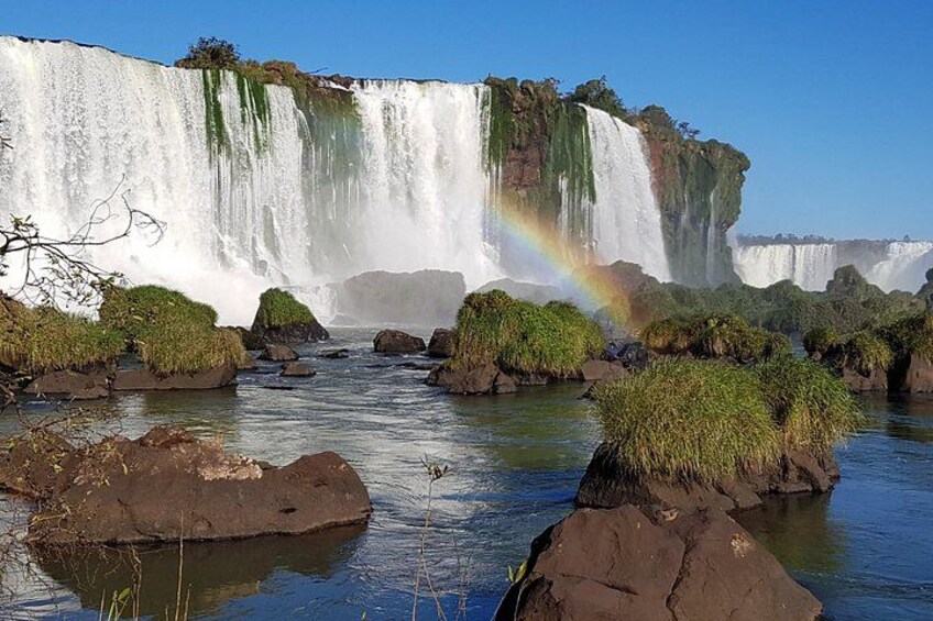 Una cascada imponente con un arcoíris, rodeada de rocas y vegetación. 1