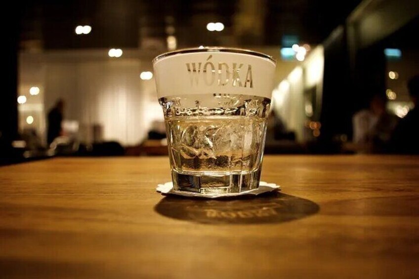 A glass of vodka on a wooden table with a blurred background. 1
