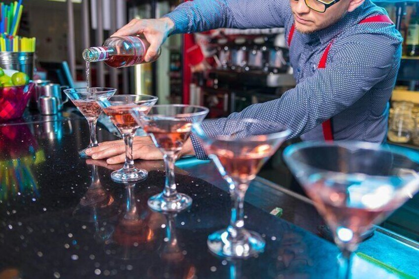 A bartender pouring a drink into a martini glass. 3