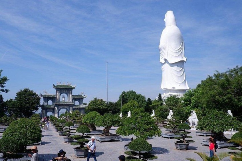 A large white statue, a pagoda, and neatly arranged potted trees. 1