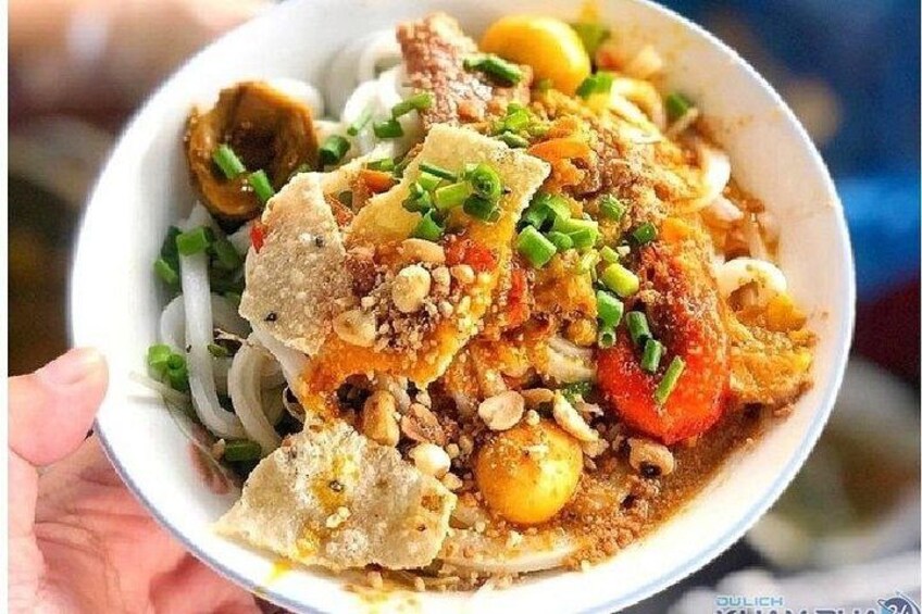 A bowl of noodle dish with toppings. 3