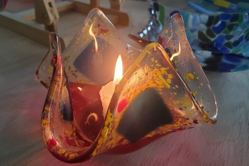 A glass candle holder with a lit candle inside. 1