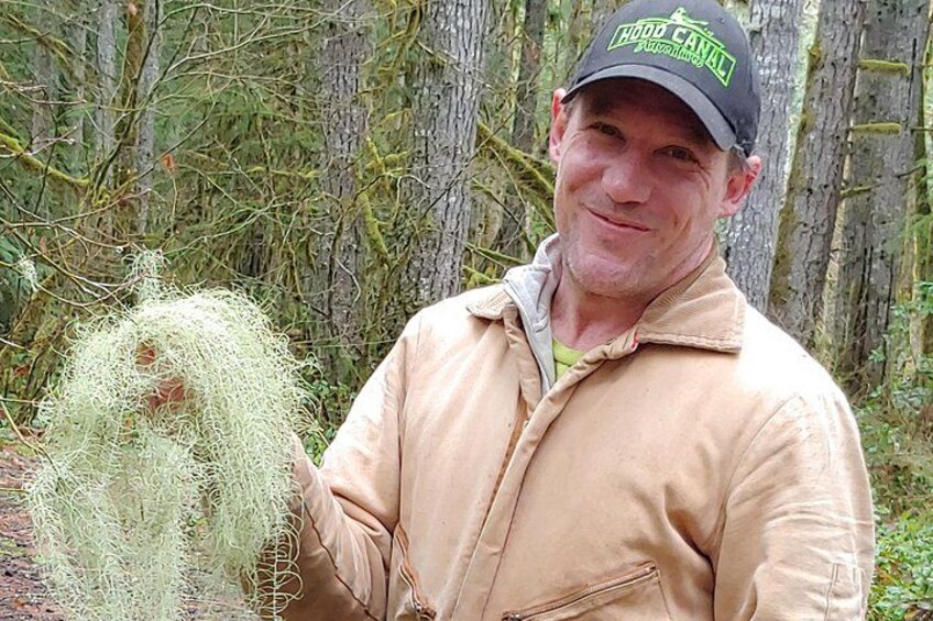 A person holding a plant in a forested area. 5