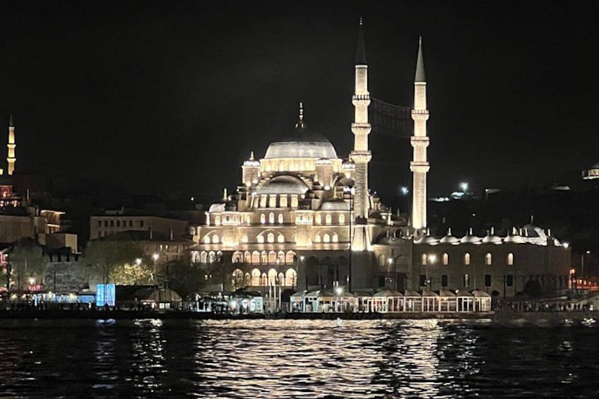 Une mosquée dotée de deux minarets et d’un dôme, illuminée la nuit. 1
