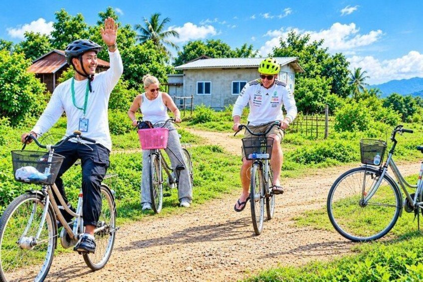 Tre cyklister på en grusvej med grøn vegetation og et hus i baggrunden. 5