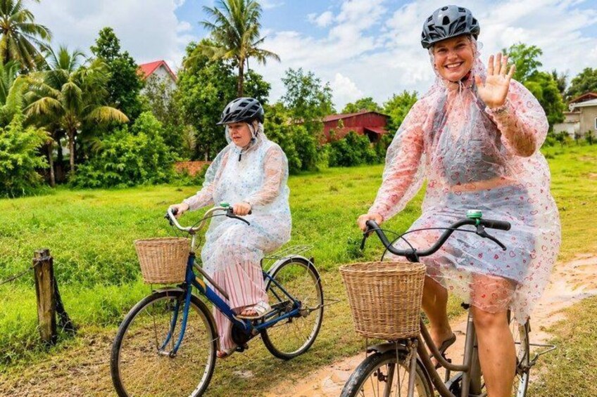 To personer på cykel i et landligt område med grønt og huse i baggrunden. 4
