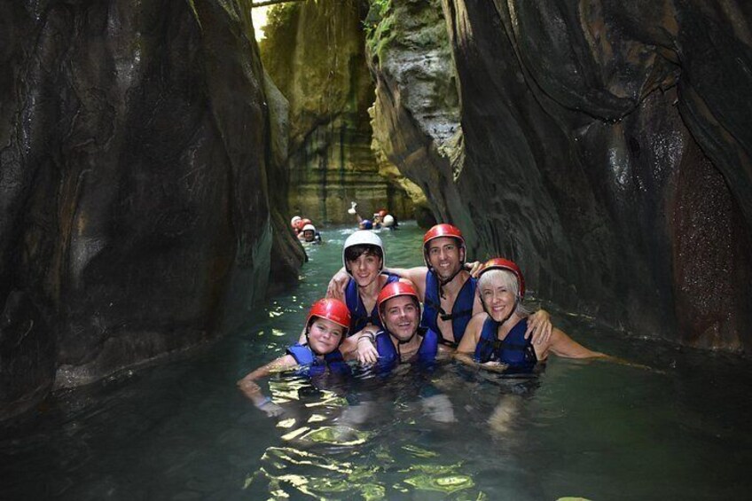 A group of people in a cave with water, wearing helmets and life jackets. 4