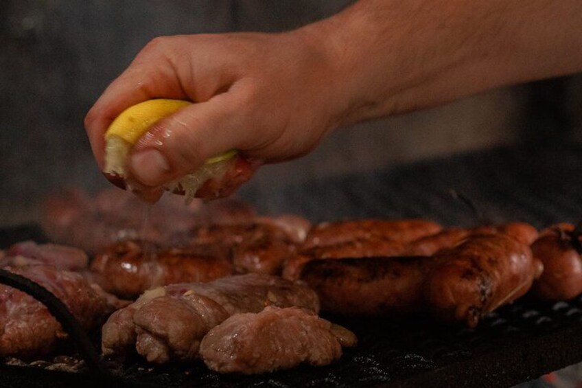 A hand squeezing lemon over grilled sausages. 2