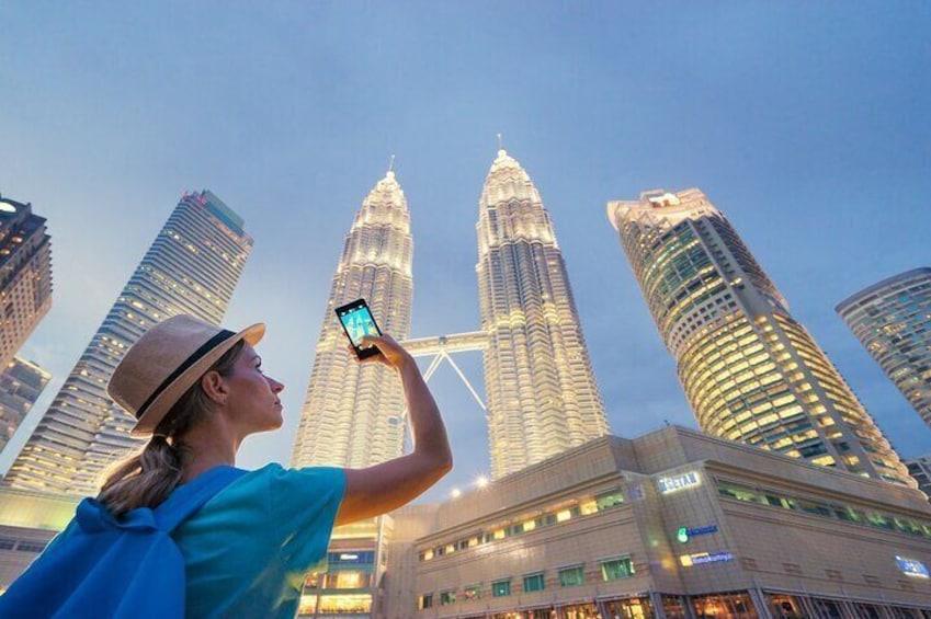 A person taking a photo of the Petronas Towers. 4