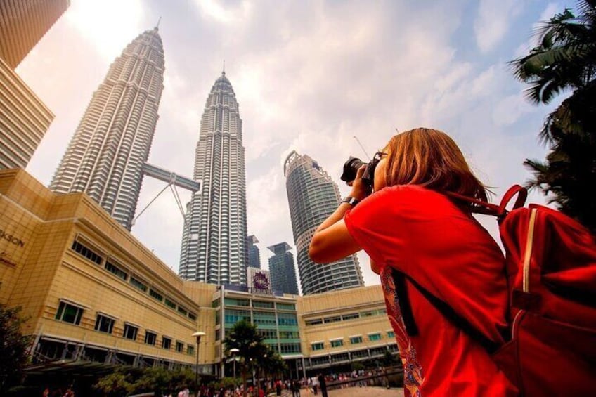 A person taking a photo of the Petronas Twin Towers. 2