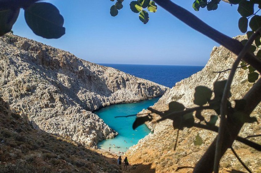 A rocky coastline with a turquoise bay, rugged cliffs, and sparse vegetation. 1