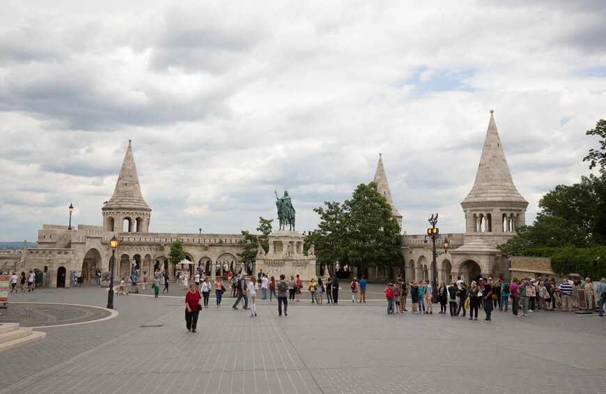 A historical square with a central monument, surrounded by tourists and classical architecture. 2