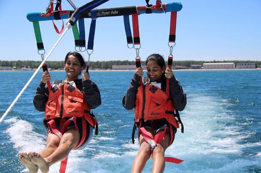 Two people on a swing ride over water, wearing life jackets. 4
