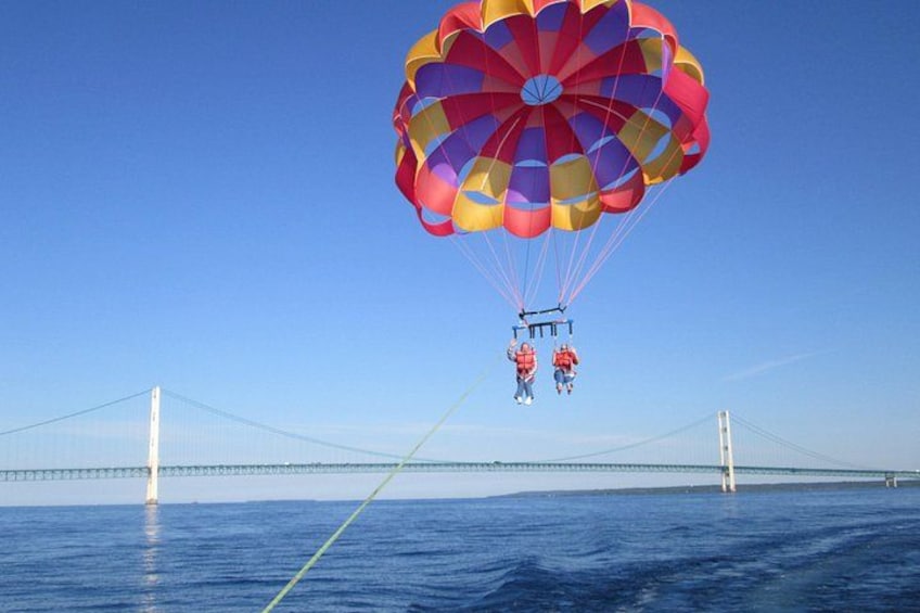 A person parachuting over a bridge with a colorful parachute. 1
