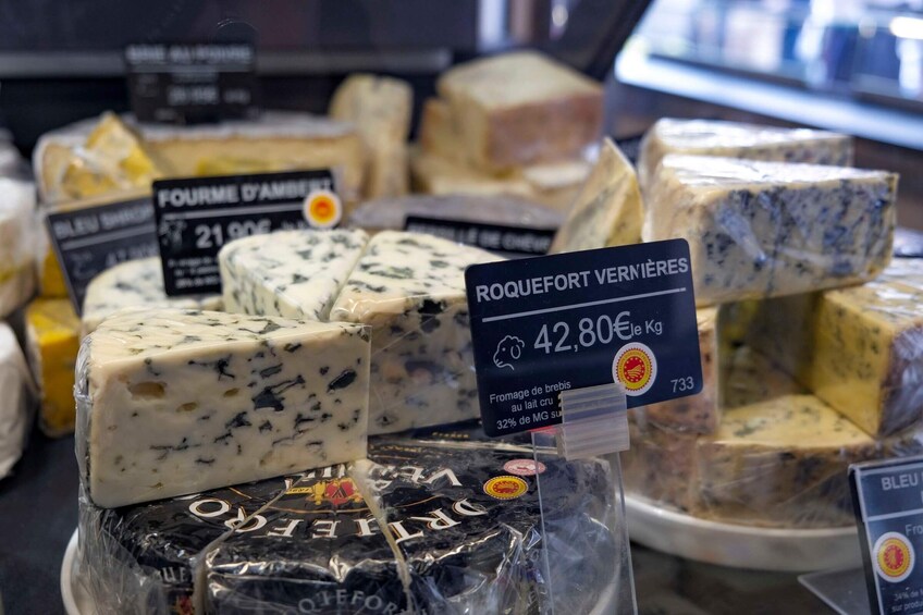 Verschiedene Käsesorten werden in einem Geschäft präsentiert, darunter Roquefort und Fourme d'Amiens. 5