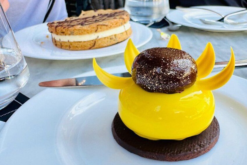 En dessert på en tallrik med en gul botten och en chokladkula ovanpå, omgiven av gula "vingar". 3