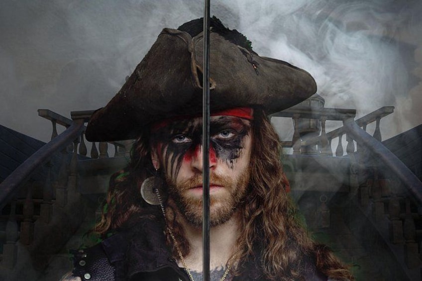 A person with a pirate hat and face paint, standing in front of a building with a balcony. 3