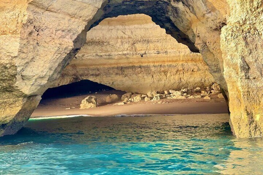 A natural rock arch over a beach with clear blue water. 5