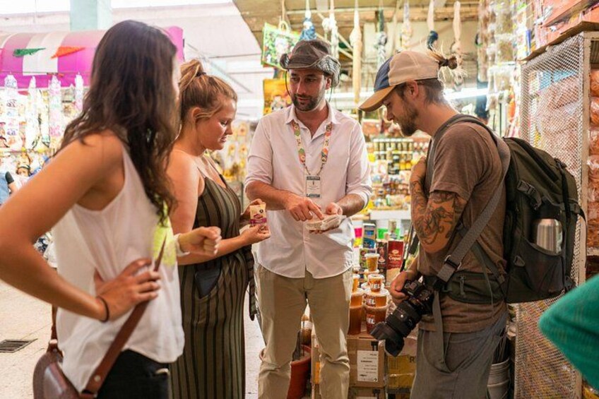 Un groupe de personnes fait ses courses dans un marché où sont exposés divers produits alimentaires et autres articles. 5
