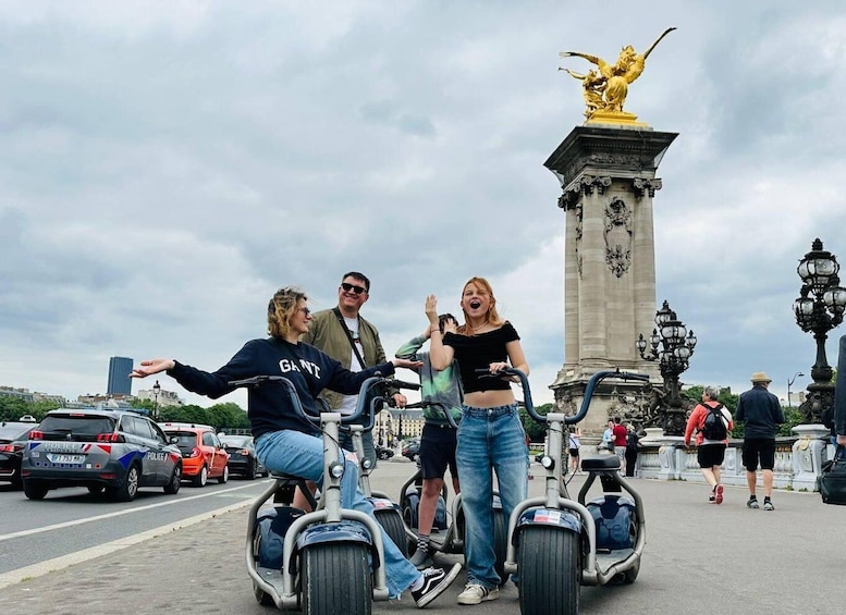 Personas en segways frente a un monumento con una estatua dorada. 3